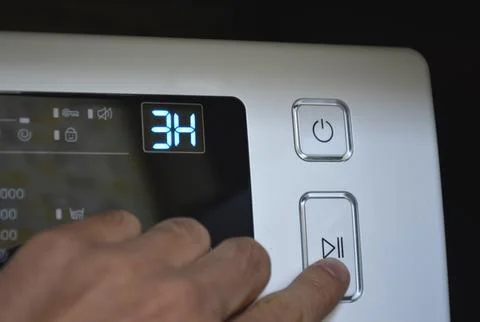 Man's hand on the start button of the washing machine Stock Photos