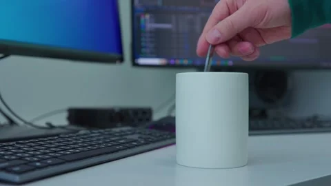 A man's hand start stirring a liquid with a spoon in a white mug Stock Footage 273794700