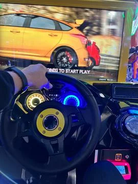 A man's hand is on the steering wheel of a racing game. Game simulator of a.. Stock Photos