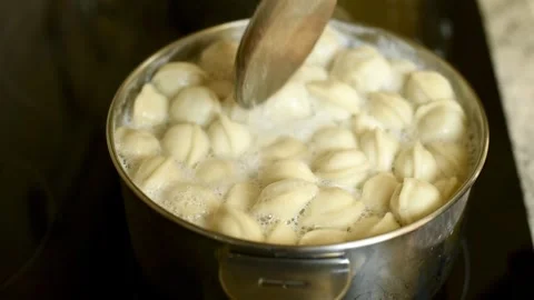 A Mans Hand Stirs Boiling Dumplings Stock-Footage 314708597