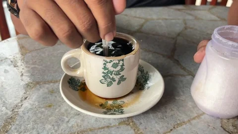 A man's hand stirs coffee in a ceramic cup Stock Footage 277683796