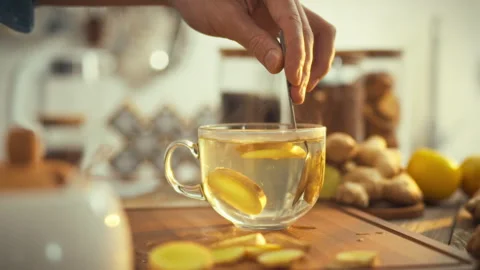 A mans hand stirs steaming ginger tea in a warm kitchen on a sunny day relea Stock Footage 331309860