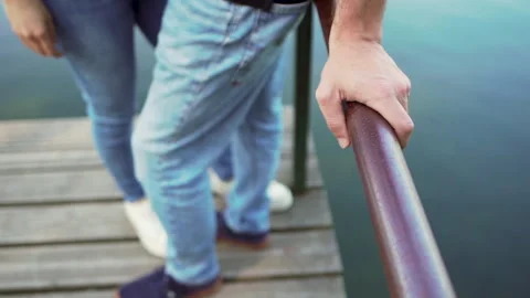 Man's hand supporting him on walkway pole with woman leaning against him by Видео 280122620