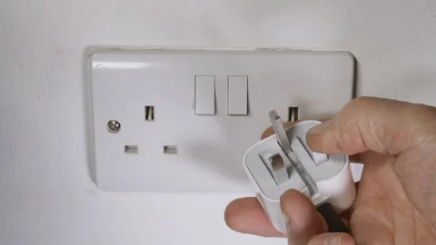 Man’s hand switching off and removing UK British travel plug from wall socket. Stock-Footage 281083103
