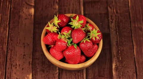 Man's hand take red ripe strawberry in wooden bowl on wooden table Stock Footage 63866262