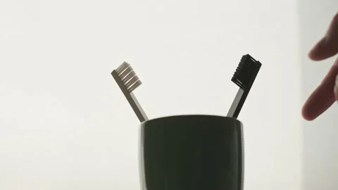 A man's hand takes and returns a toothbrush from a mug. Vídeos de archivo 135791105