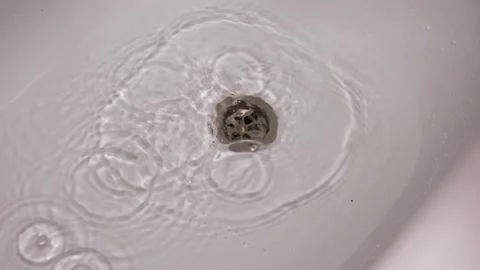 A man's hand takes the blue plug out of the drain in the tub and the water Stock Footage 168599274