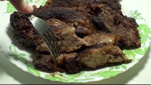 Man's hand takes a fork with a piece of fried meat from a plate Stock Footage 79782625