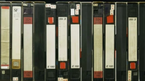 A man's hand takes one of the videotapes on the shelf Stock Footage 162854099