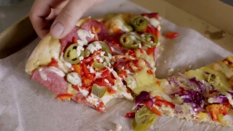A man's hand takes an over-flavored piece of pizza Stock Footage 83136568