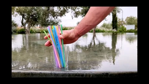 Mans hand takes plastic cocktail tubes from glass and put back bamboo tubes Stock Footage 310083584