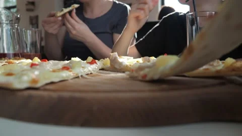 A man's hand takes a slice of pizza. a woman with a child in the background is Stock Footage 158634172