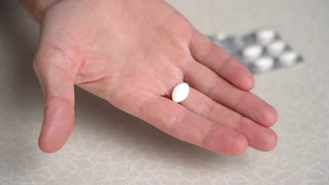 Man's hand takes white tablet lying near blister from table and points to camera Vidéo 233821802