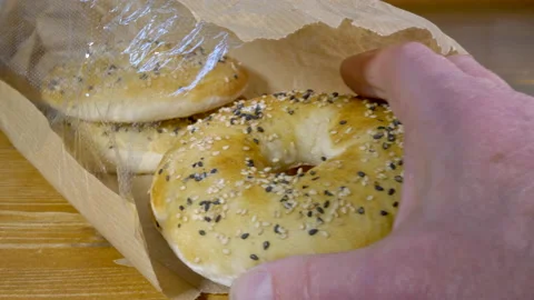 Man’s hand taking a fresh bagel shaped barbari bread from four in paper packet. Stock Footage 154404175