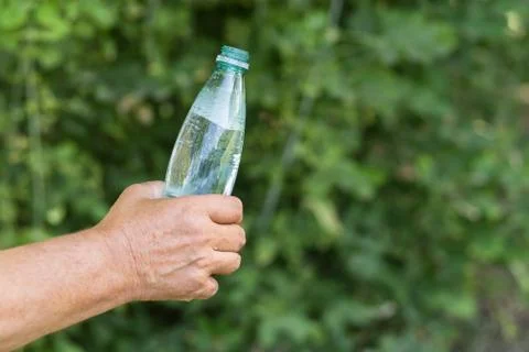 Man's hand taking opened bottle of mineral water Stock Photos