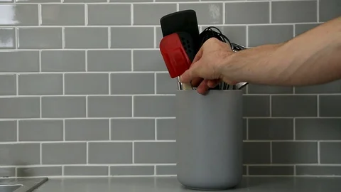 Man's hand taking out a red spatula from a jar of kitchen utensils. Stock Footage 115329535