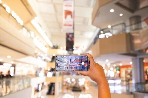 A man's hand taking pictures of objects in the mall. the man is seen using .. Stock Photos