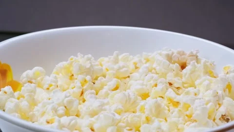 Man's hand taking popcorn from rotating bowl Stock Footage 300386026