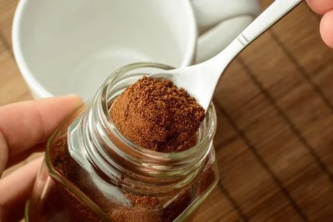 Man`s hand taking some ground coffee from coffee jar Stock Photos