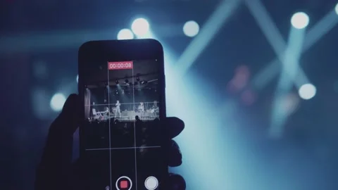 A man's hand is taking a vertical video for a music band performing on stage. Video stock 145977682