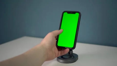 A mans hand taps and swaps on a green screen. A smartphone on a magnetic station Stock Footage 314465617