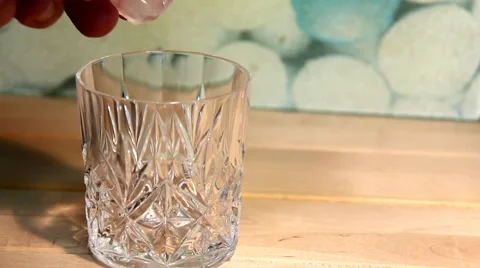 Man's hand throwing ice cubes in a glass beaker 1 Stock Footage 47073803