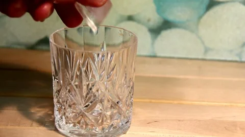 Man's hand throwing ice cubes  in a glass beaker 2 Stock Footage 47074112
