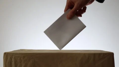 Man's hand throws a ballot paper for voting at a polling station during election Stock Footage 141392299