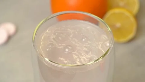 Man's hand throws effervescent vitamin C into glass of water, bubbles rise 库存影片 234459507