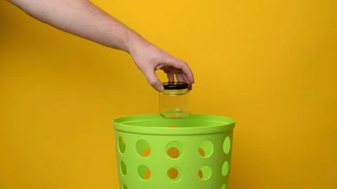 A man's hand throws a glass jar into a green trash Stock Footage 194566382