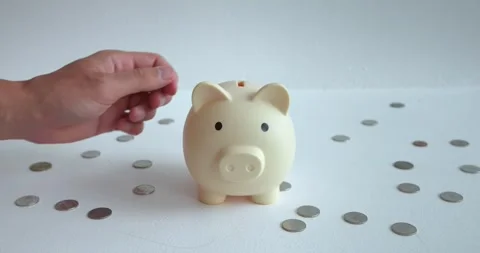 Mans hand throws money into ceramic piggy bank. Piggy bank is associated with Stock Footage 270416733