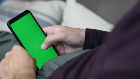 Man's hand touches and scroll holding an Smartphone with green screen. Video stock 162404261