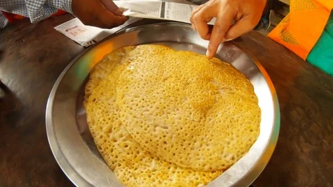 Man`s hand touches rice flat cake on plate wooden table newspapers close up Assa Stock Footage 113674622