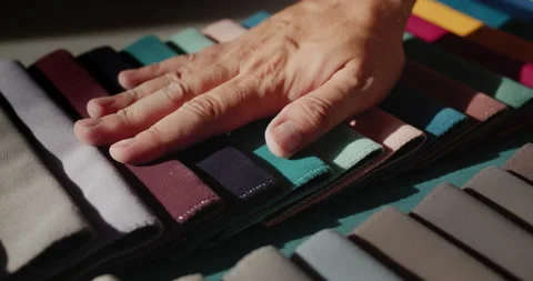 A man's hand touches samples of multi-colored fabric. Designer selects textiles Stock Footage 159164037