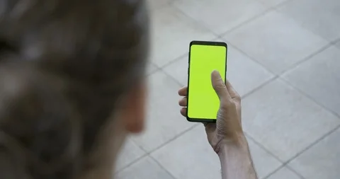 Mans hand touching and scrolling green screen on a smartphone Stock Footage 97877495