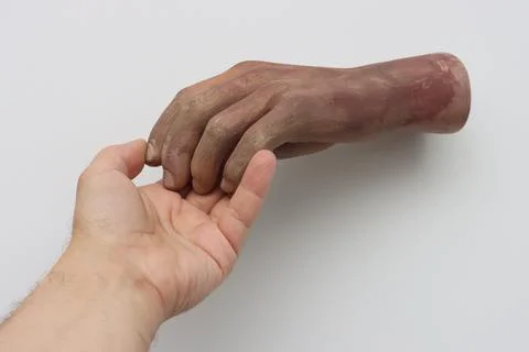 Man's hand touching the artificial hand from a large doll Stock Photos