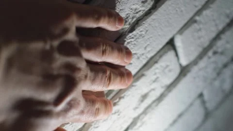 A man's hand touching a wall with a facing light brick, close-up Stock Footage 262643698