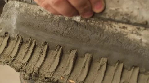 Mans hand with trowel applied tile adhesive. Repairman making repairs in Stock Footage 148858054