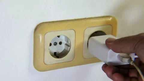 Man's hand trying to plug a cell phone charger to the electrical socket. Stock Footage 338446253