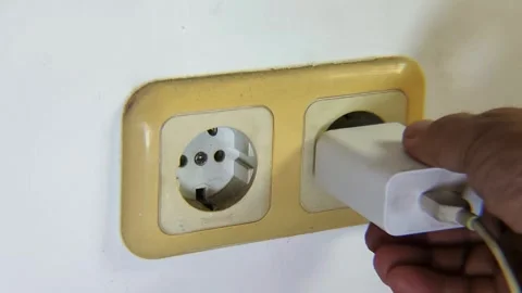 Man's hand trying to unplug a cell phone charger to the electrical socket. Stock Footage 338446249