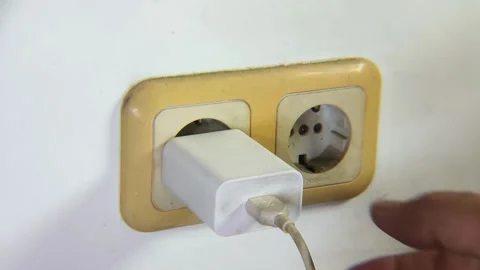 Man's hand trying to unplug a cell phone charger to the electrical socket. Stock Footage 338447096