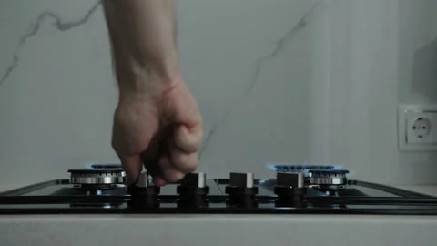 Man's hand turn on control knobs and lights fire on all 4 gas burners in modern 스톡 동영상 176728315