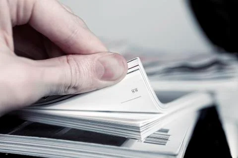 Man's hand turned over a stack of magazines 스톡 사진