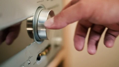 Man's hand turning a dial to increase and decrease volume on hifi stereo 库存影片 94833379