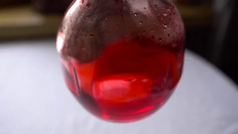 Man's hand turns the flask with red chemical Stock Footage 73792773