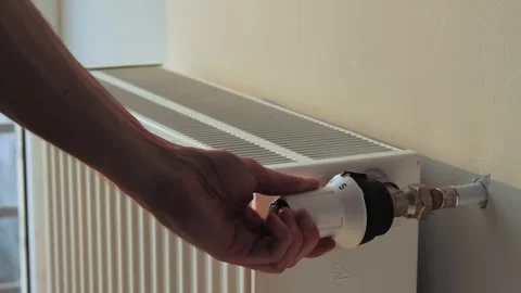 Man's hand turns off the heating by setting the thermostat of the radiator 库存影片 242503402