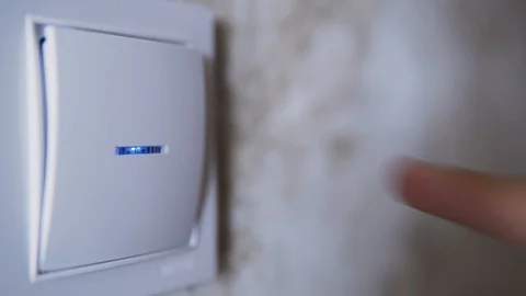 A man's hand turns on the light by pressing a button from the wall of the house Stock Footage 124771689