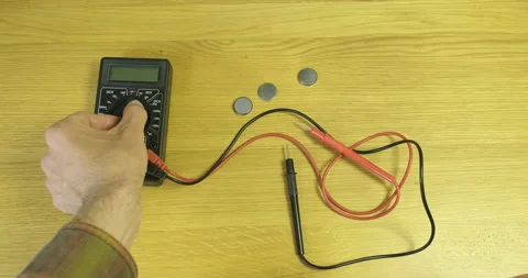 Man's hand turns on a multimeter. Close-up, top view. Wood desktop. LCD display Vídeos de archivo 198821505