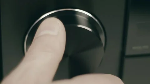 A man's hand turns a round, black, shiny volume knob on an receiver Video stock 287939320