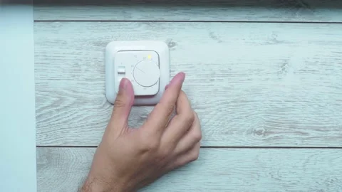 A man's hand turns the wheel of a white plastic floor heating controller Stock Footage 165266930